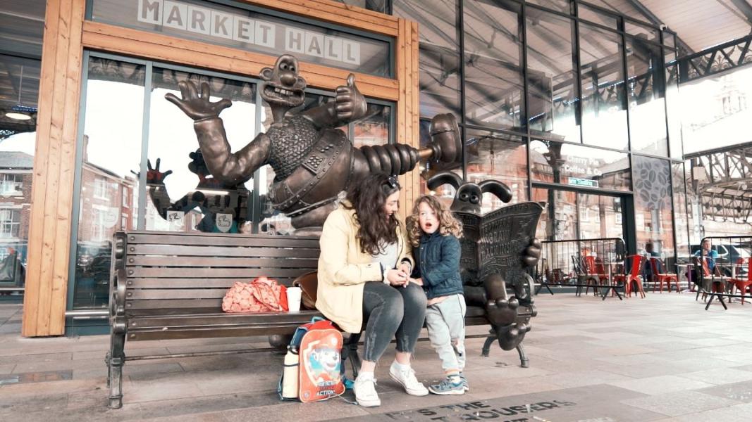 Mother and child on Wallace and Gromit bench outside Preston Market Hall