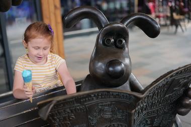 Child with ice cream interacting with Wallace and Gromit statue